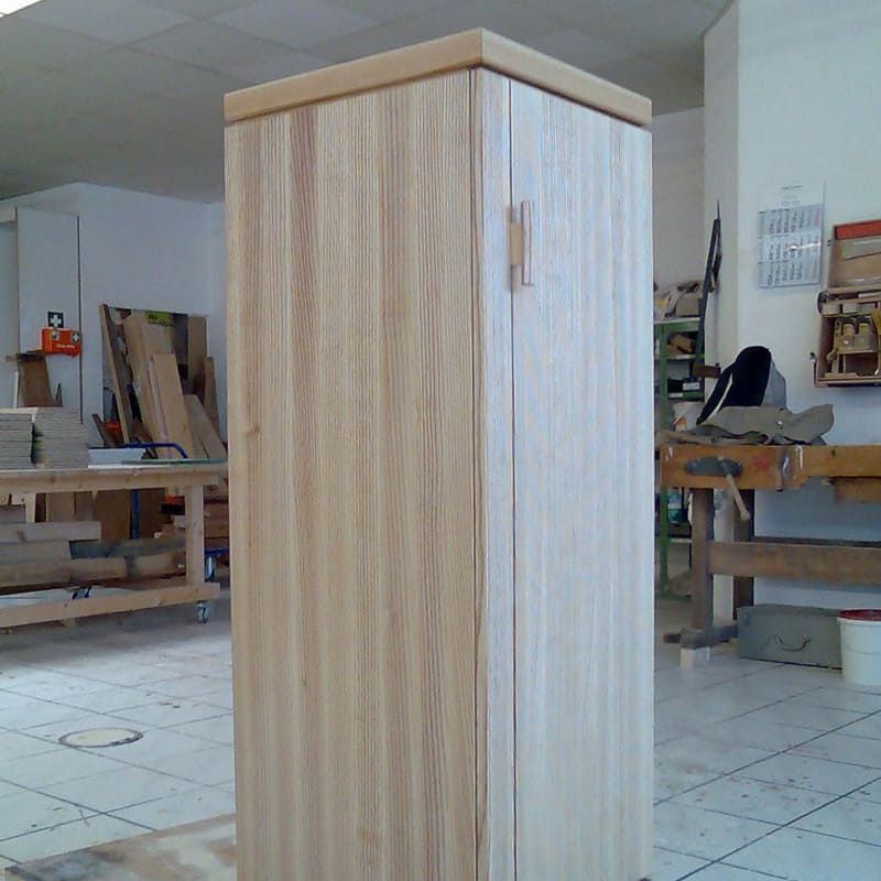 Ein Holzschrank mit einer weißen Tür in einem Zimmer