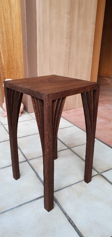 Auf einem gefliesten Boden steht ein kleiner Holztisch.