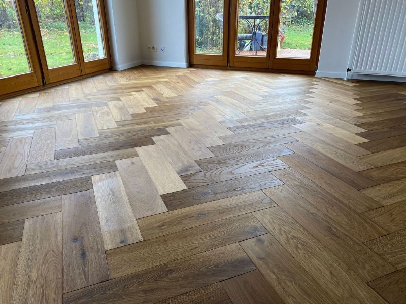 Ein Holzboden mit Fischgrätenmuster in einem Wohnzimmer.