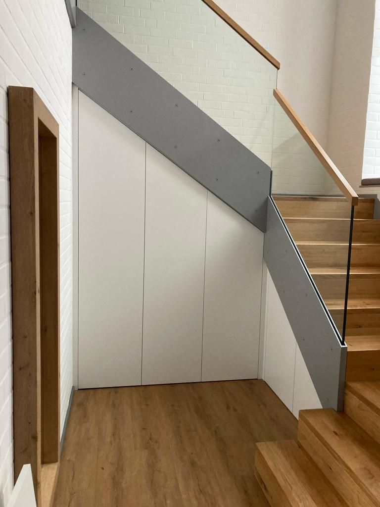 Eine Holztreppe mit einem Glasgeländer in einem Flur.