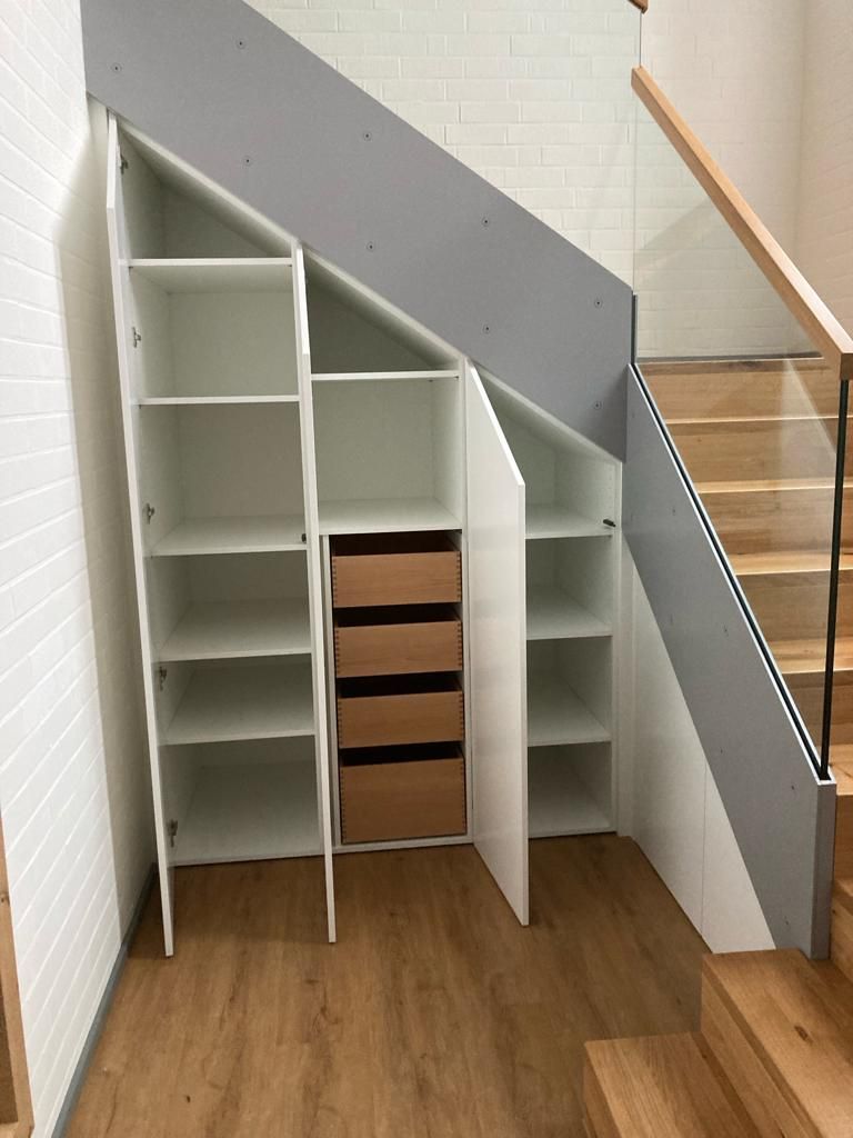 Ein Schrank unter einer Treppe mit Schubladen und Regalen