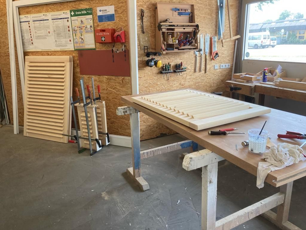 Ein Holztisch mit einem Stück Holz darauf in einer Werkstatt.