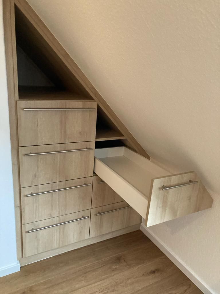 Eine Kommode unter einer Treppe mit einer geöffneten Schublade.