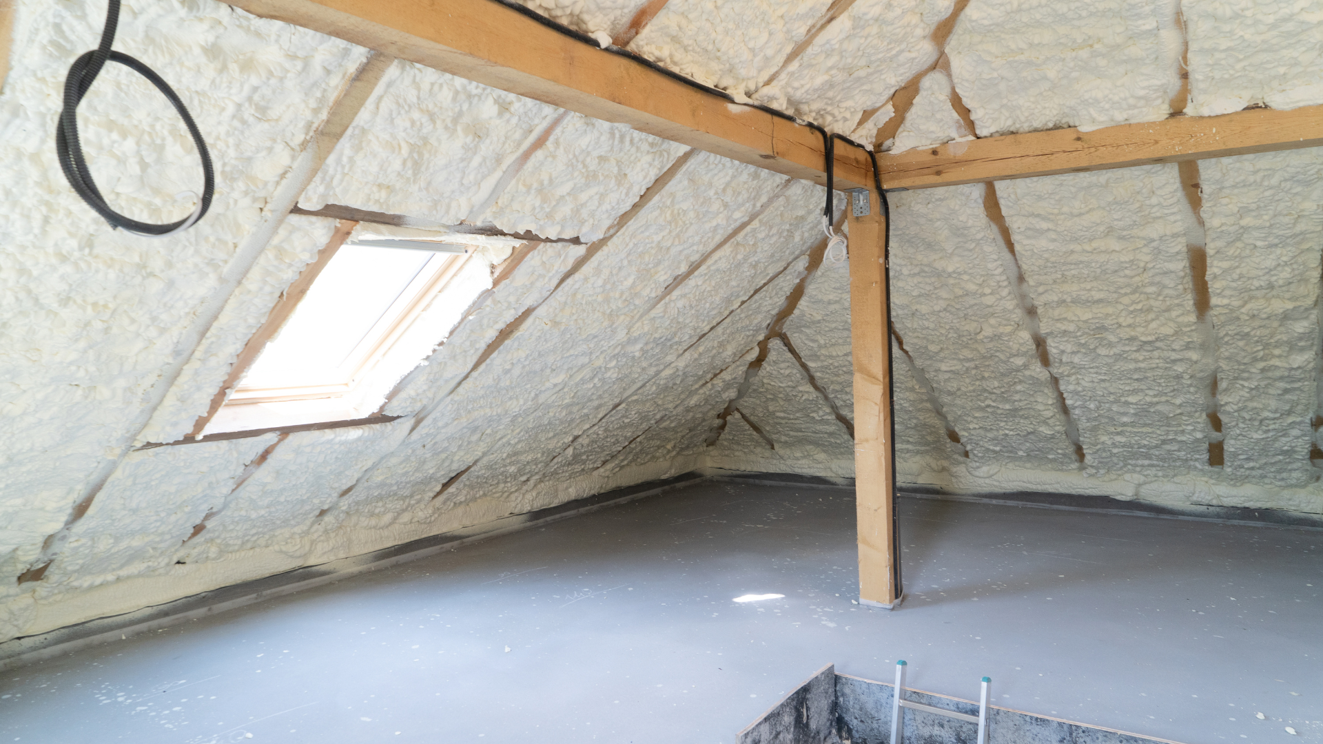 Combles isolés par mousse de polyuréthane projetée sur le toit et sol en béton. Puits de lumière visible.