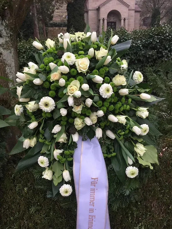 Blumengesteck auf einer Beerdigung mit Schärpe