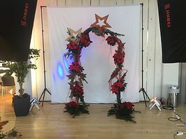 Weihnachtlicher Torbogen für ein Fotoshooting mit Sternen und Christblumen geschmückt
