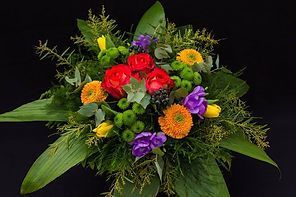 Bunter sommerlicher Blumenstrauß in kräftigen Farben mit Palmblättern