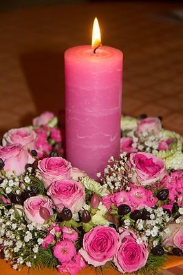 Rosa Kerze mit einem Kranz aus Rosa-Rosen drumherum