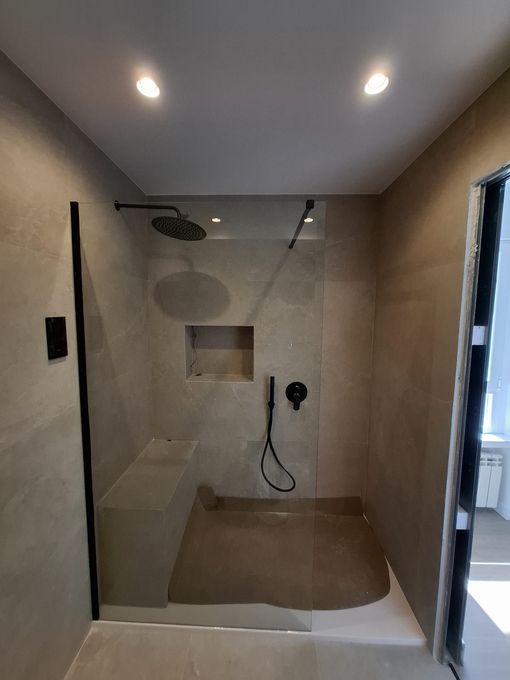 Un baño con ducha a ras de suelo y un banco.