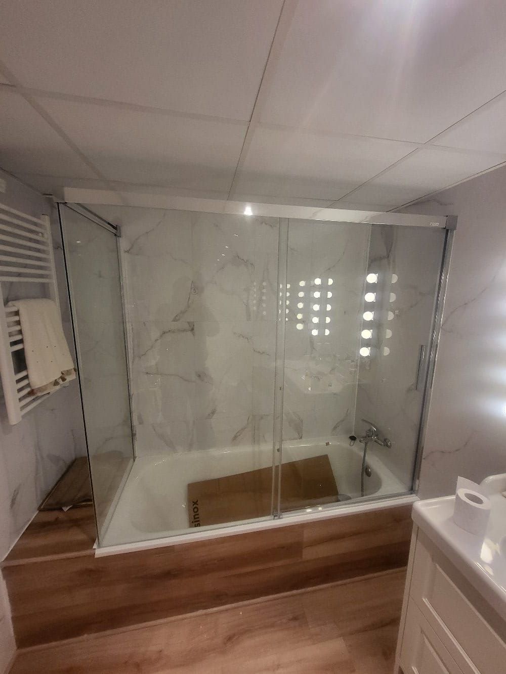 Un baño con bañera y puerta de ducha de cristal.