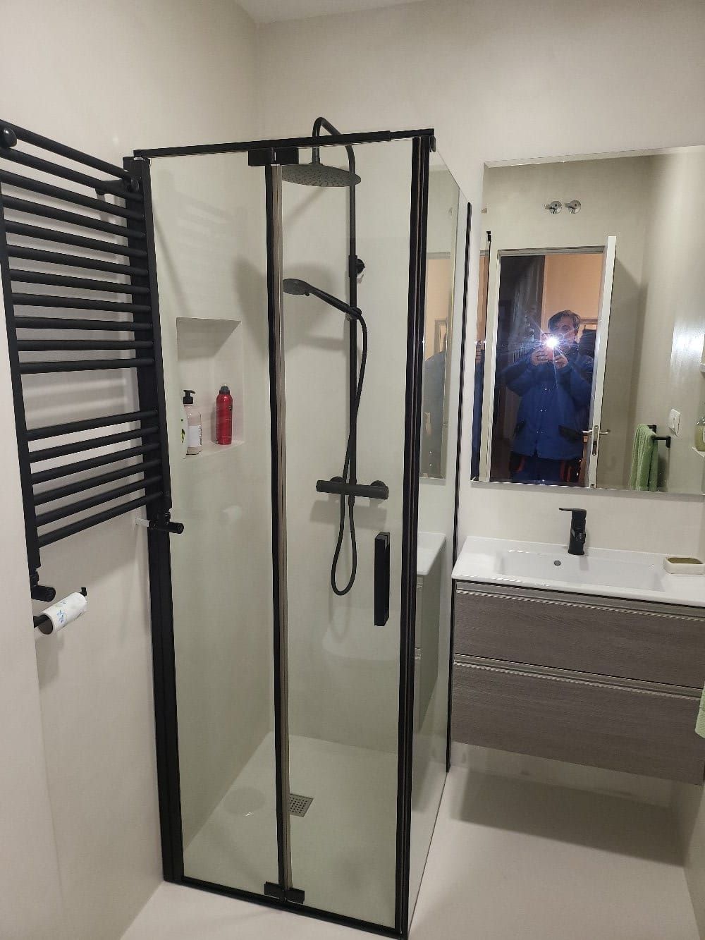 Un baño con ducha, lavabo, espejo y toallero.