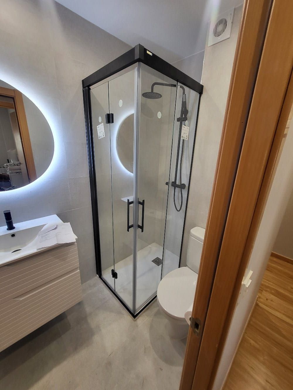 Un baño con ducha, inodoro, lavabo y espejo.