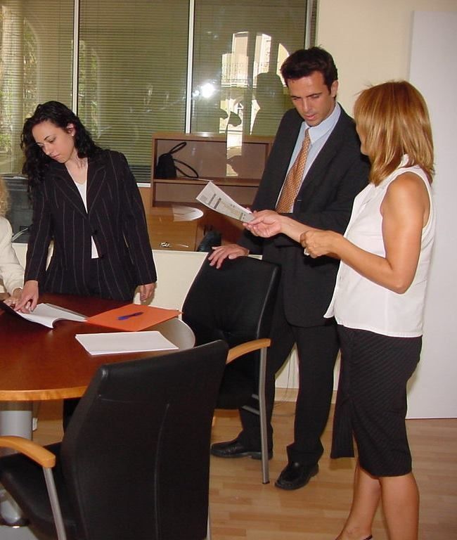 Un grupo de personas de pie alrededor de una mesa mirando papeles.