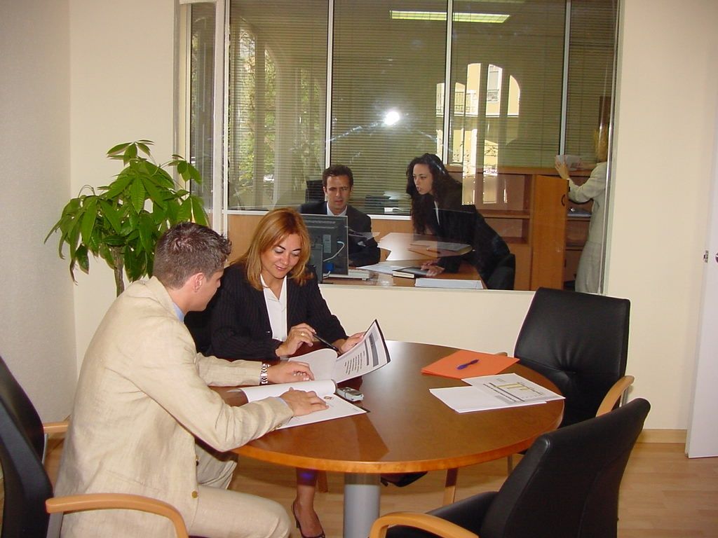 Un grupo de personas están sentadas alrededor de una mesa mirando papeles.