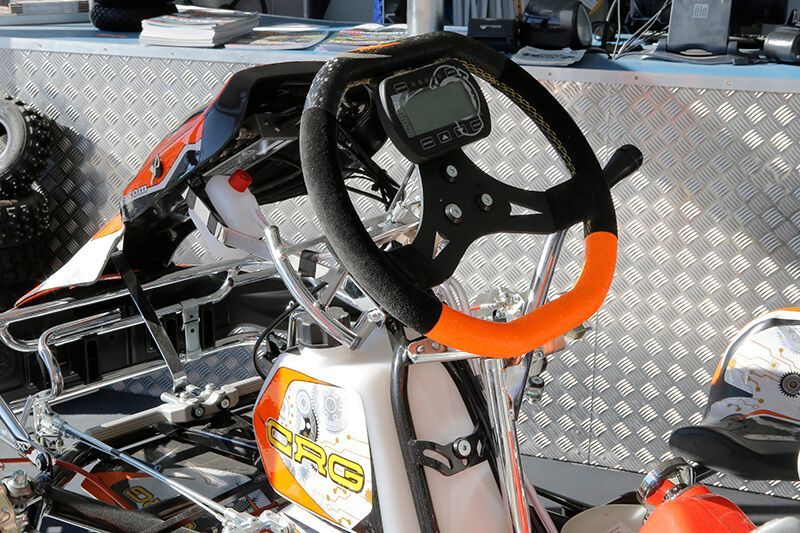 Go-Kart-Cockpit mit schwarz-orangefarbenem Lenkrad, Digitalanzeige.