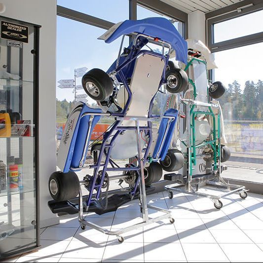 Go-Karts auf Ständern in einem Geschäft; ein blaues im Fokus, ein grünes rechts.