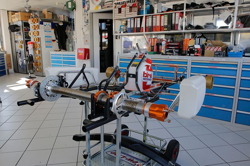 Go-Kart-Chassis auf einem Ständer in einer Werkstatt mit Werkzeugen und Lagerraum.