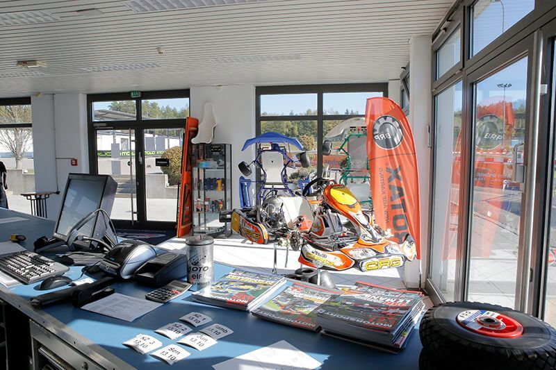 In einem Geschäft sind in der Nähe der Fenster Go-Karts, Reifen und Rennmagazine ausgestellt.