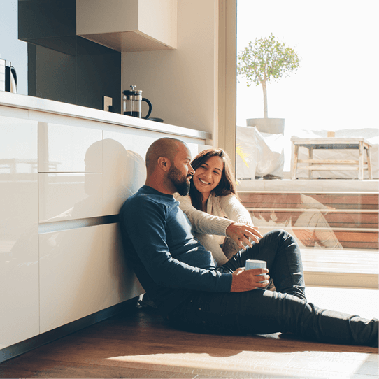 Ein Mann und eine Frau sitzen in einer Küche auf dem Boden.