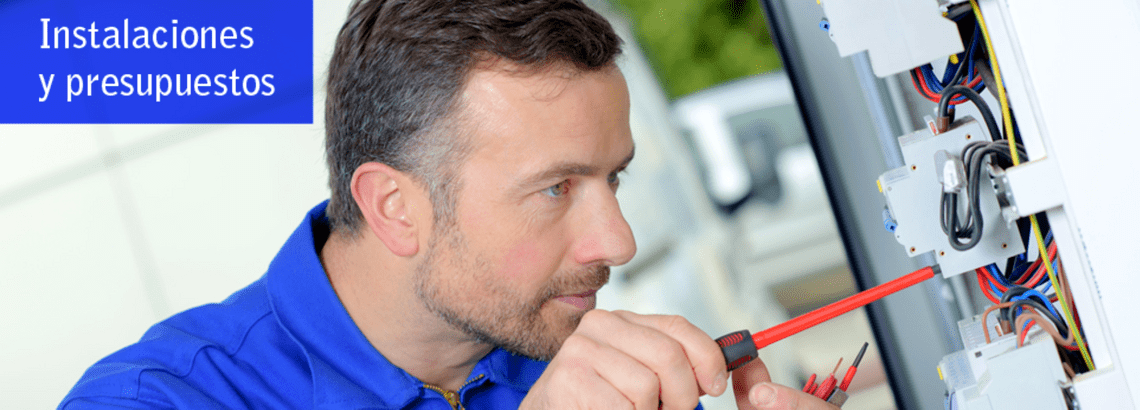Hombre trabajando en un panel eléctrico con un destornillador. Camisa azul. Texto: Instalaciones y presupuestos.