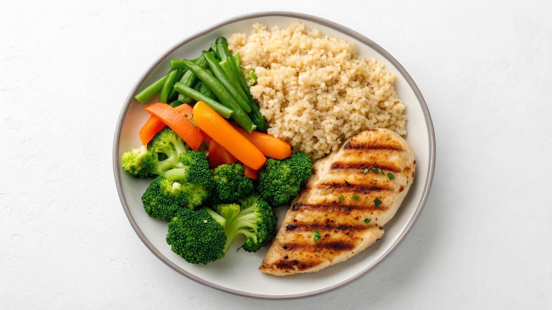 Assiette avec poulet grillé, riz brun, brocoli, haricots verts et carottes.