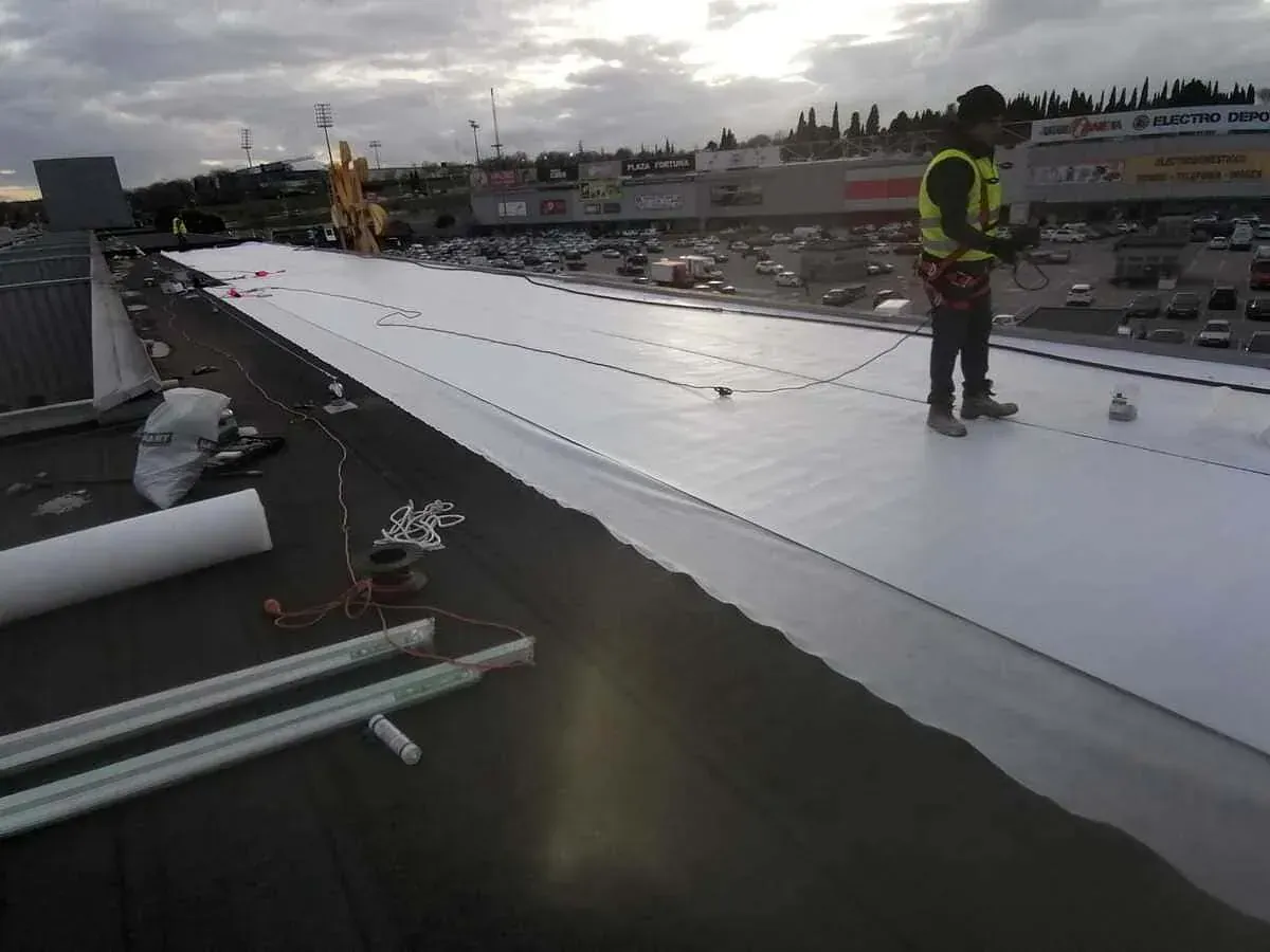 Un hombre está trabajando en el tejado de un edificio.