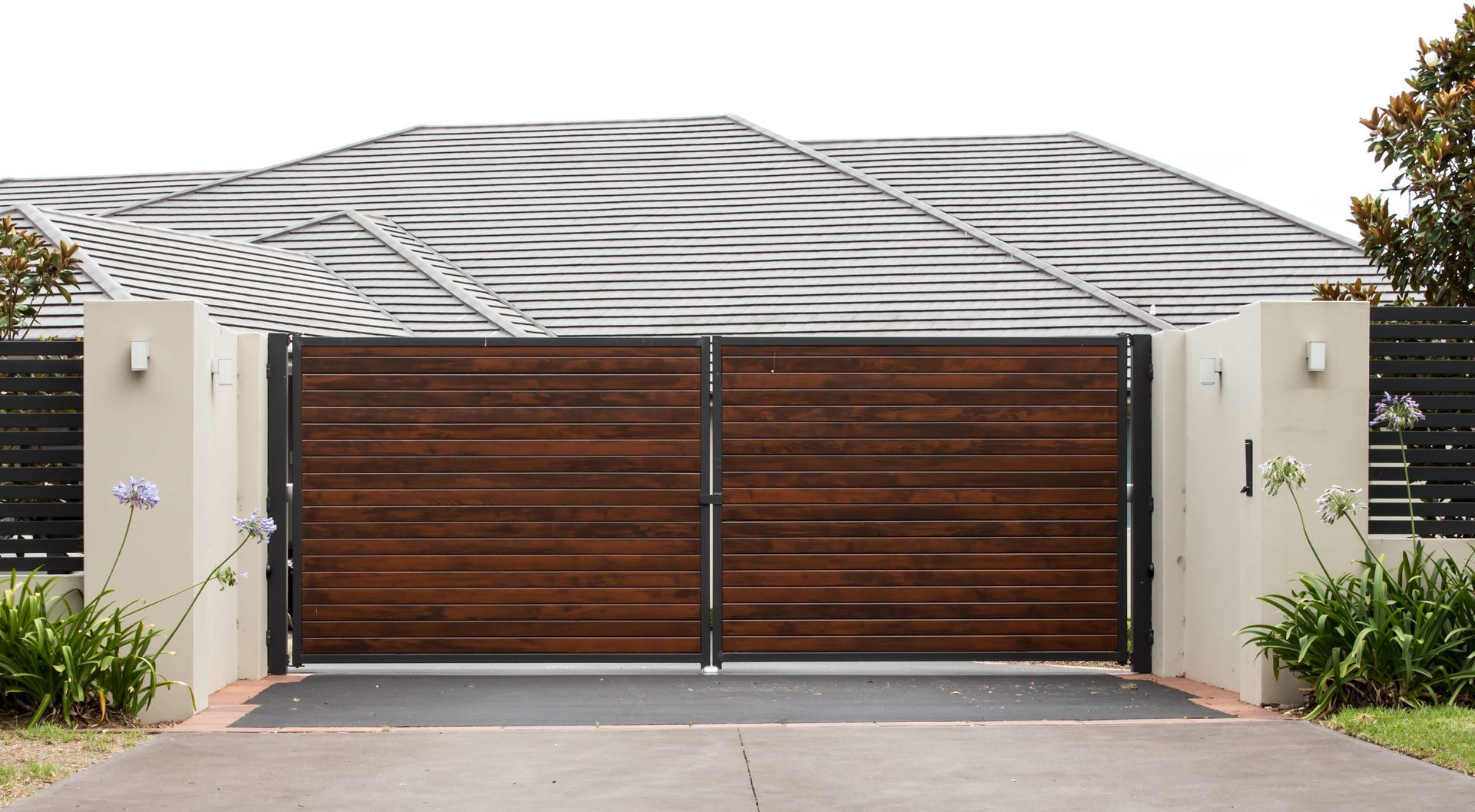 Extérieur de maison moderne avec porte de garage en bois pour deux voitures et entrée paysagée