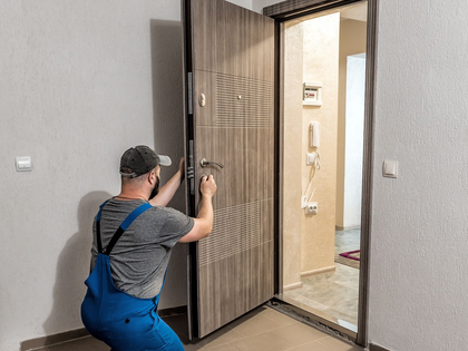 Un ouvrier installe une grande porte métallique dans l'entrée d'une maison.