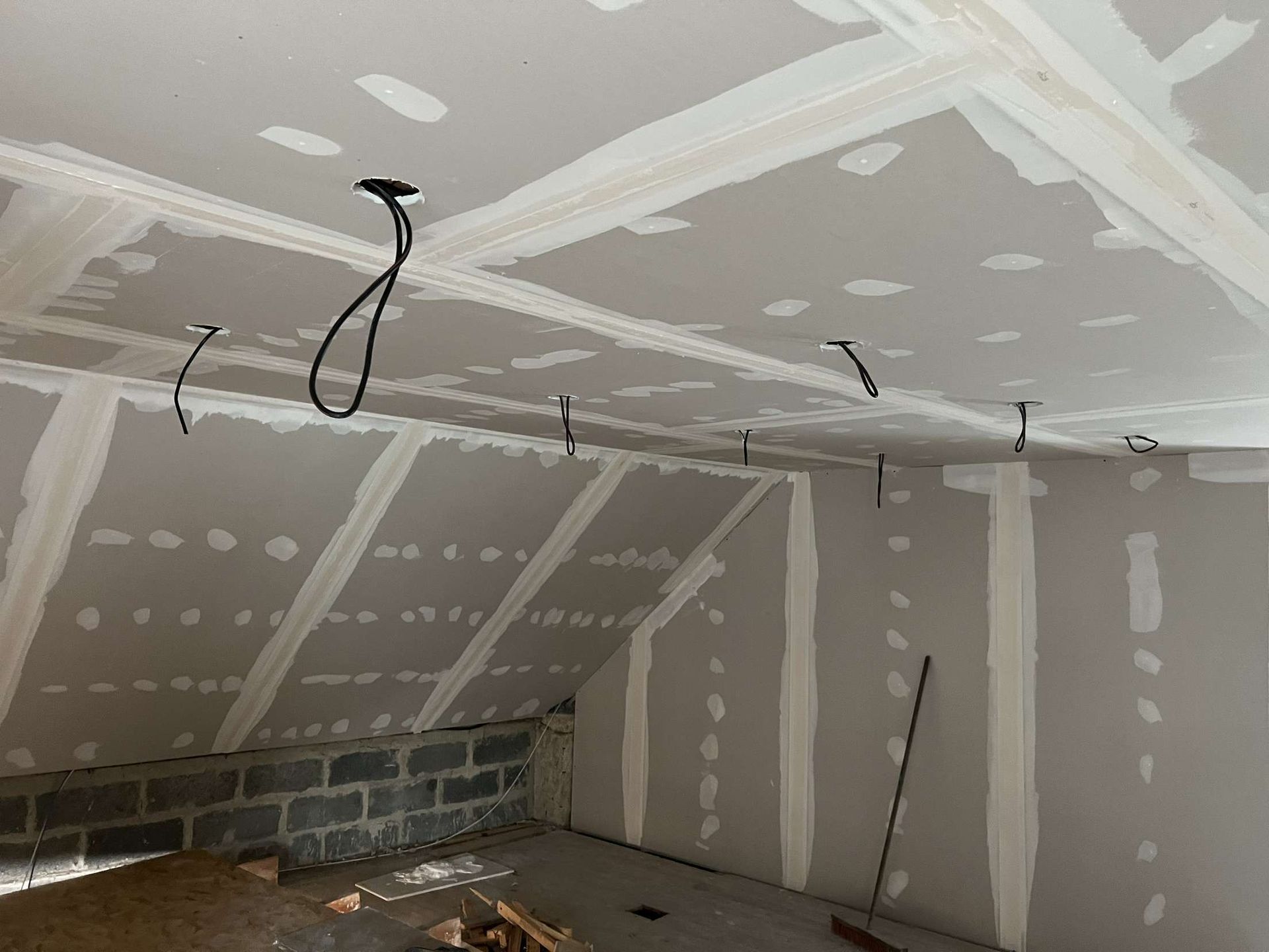 Grenier en rénovation avec porte ouverte, poutres apparentes et échelles vertes et jaunes au sol