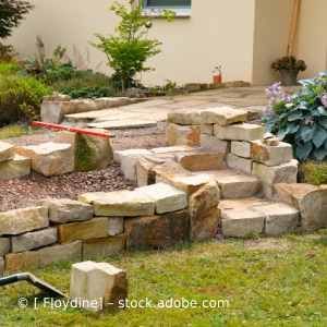In einem Garten vor einem Haus wird eine Steinmauer gebaut. Karl Müller Garten- und Landschaftsbau