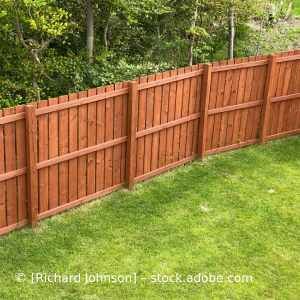 Auf einem üppigen grünen Rasen steht ein Holzzaun. Karl Müller Garten- und Landschaftsbau