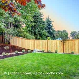 Ein Holzzaun umgibt einen üppigen grünen Rasen in einem Hinterhof. Karl Müller Garten- und Landschaftsbau