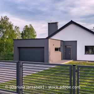 Ein modernes Haus mit einer Garage und einem Zaun davor. Karl Müller Garten- und Landschaftsbau