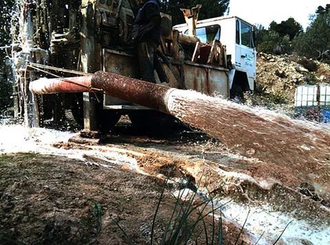 Un camión está bombeando agua de un agujero en el suelo.