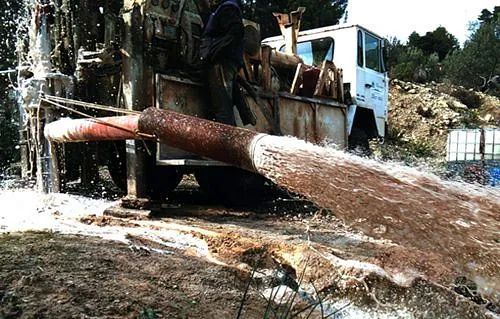 Un camión está bombeando agua de un agujero en el suelo.
