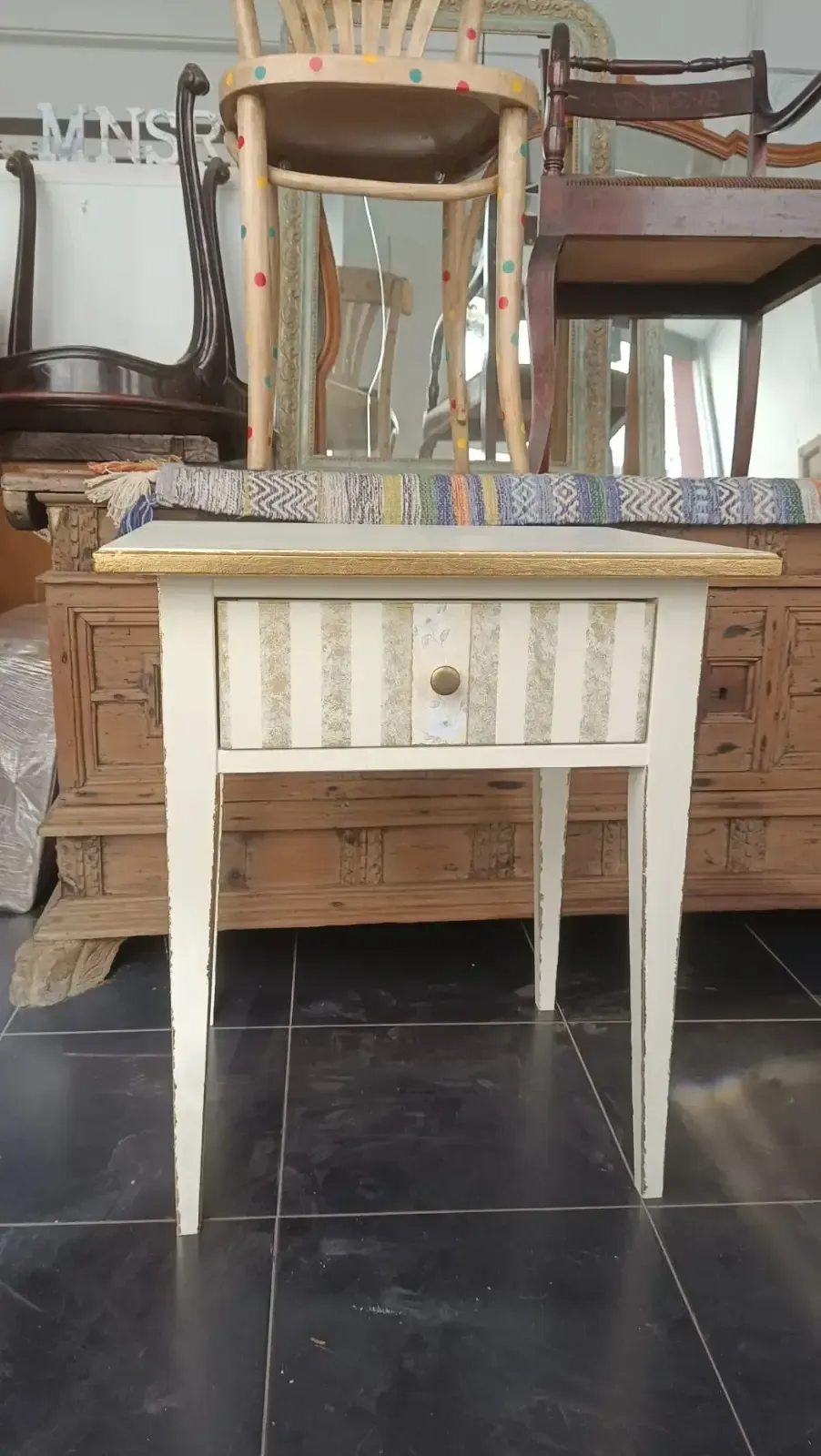 Una persona con una camisa a cuadros utiliza una brocha para aplicar el acabado al brazo de madera.