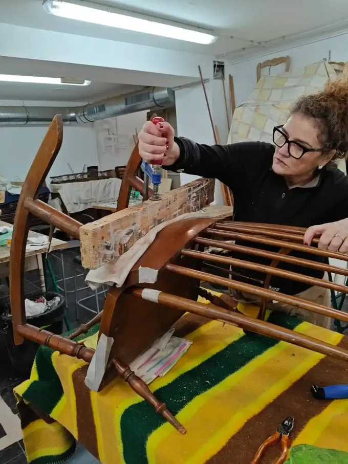 Tres personas trabajando en la restauración de muebles de madera en un taller.