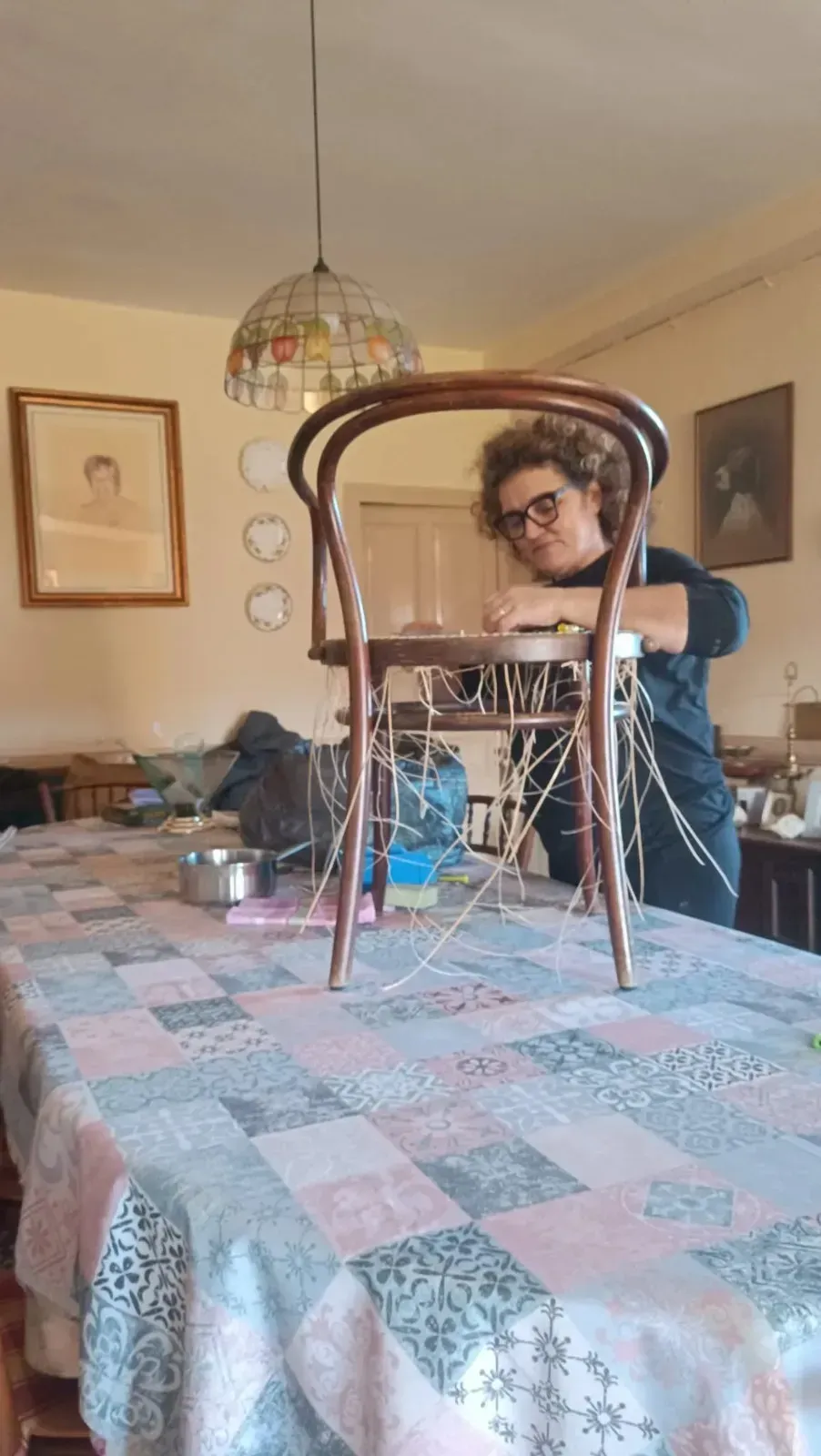 Una persona que ensambla un mueble de madera pintada de color claro, fijando husos decorativos a una tabla.