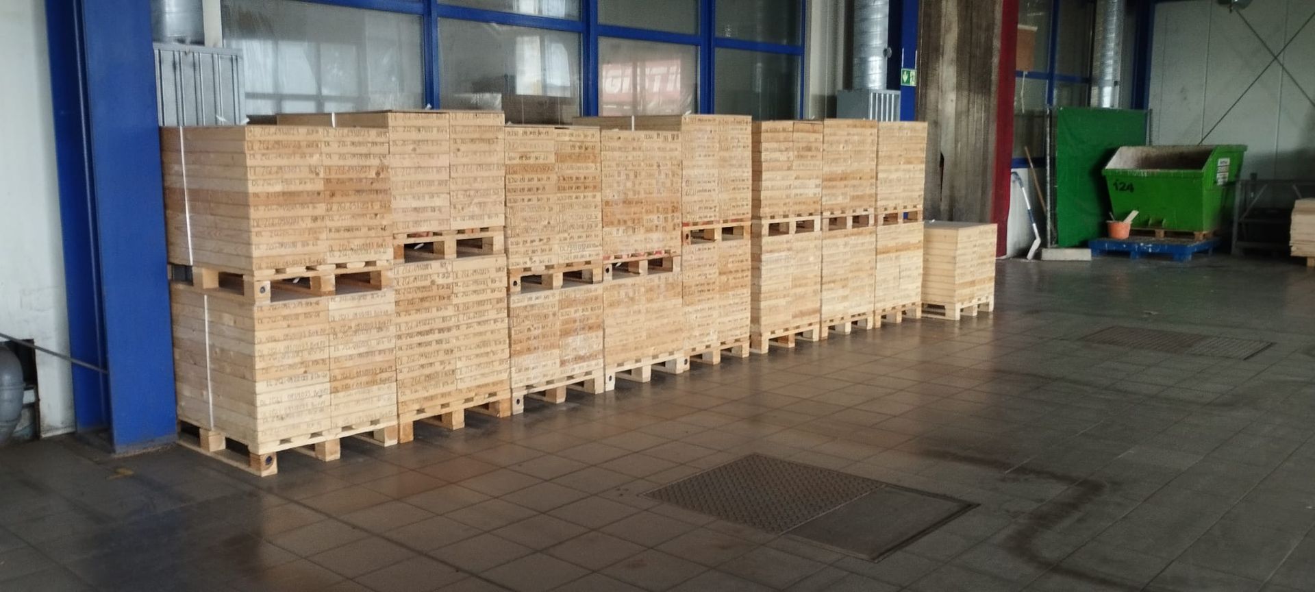 Stapel von Holzkisten auf Paletten in einer Lagerhalle.