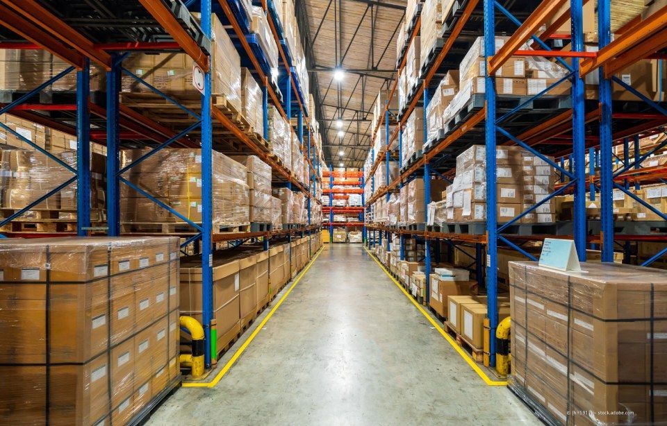Innenansicht eines Lagerhauses mit Reihen von gepackten Kisten auf hohen Regalen.