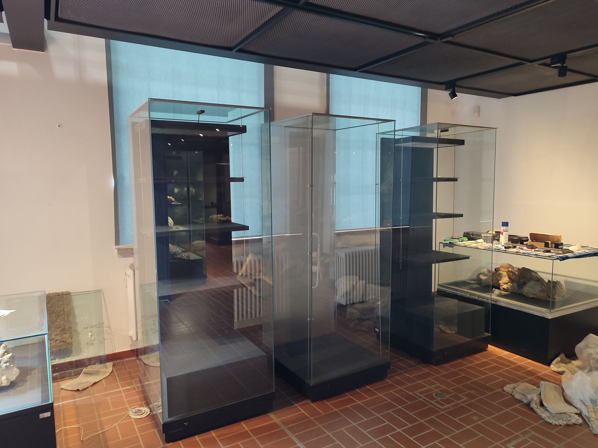 Museumsraum mit Glasvitrinen, einige leer, in der Nähe eines Fensters.