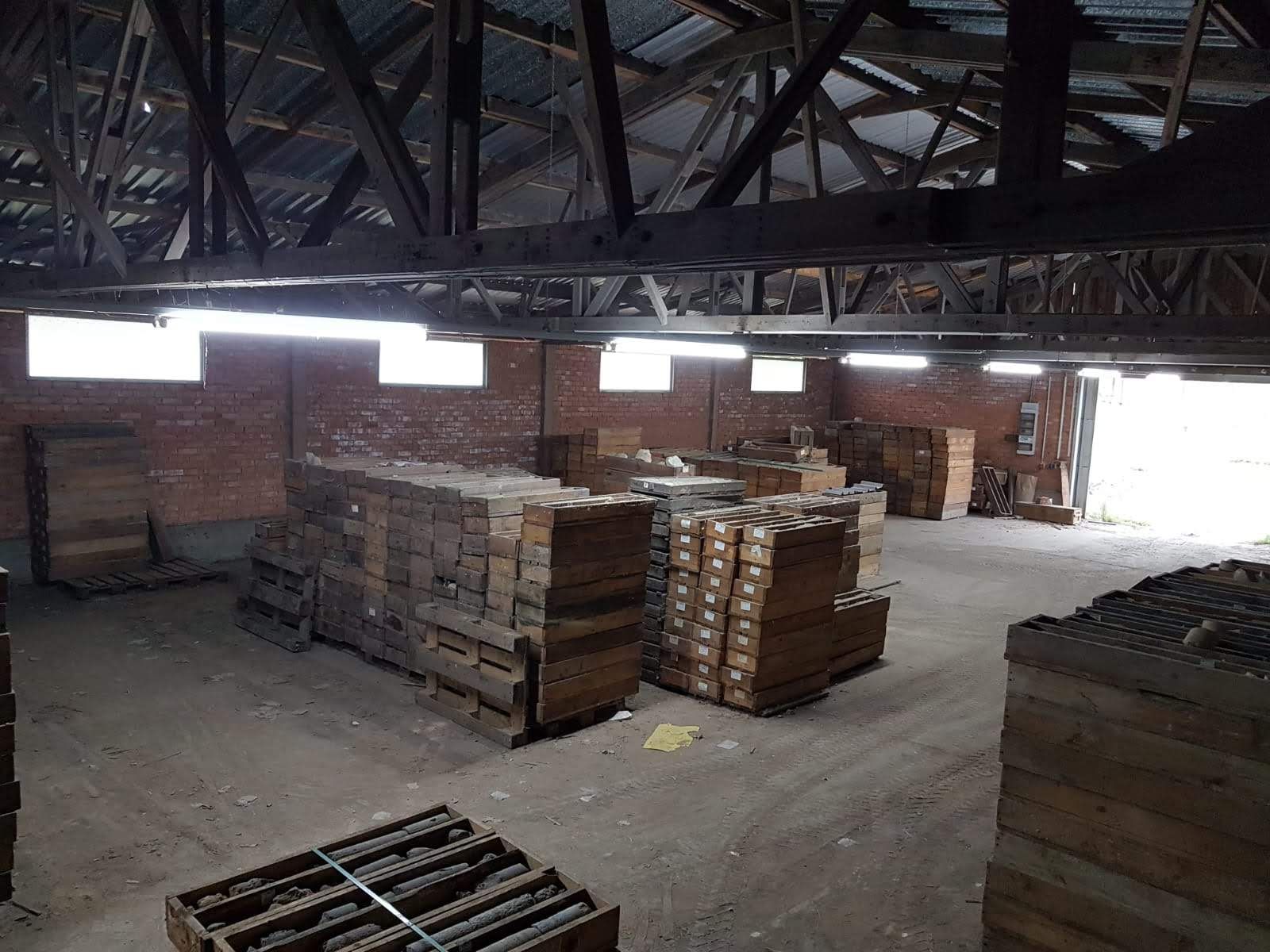 Innenansicht eines Lagerhauses mit gestapelten Holzkisten. Natürliches Licht fällt ein.