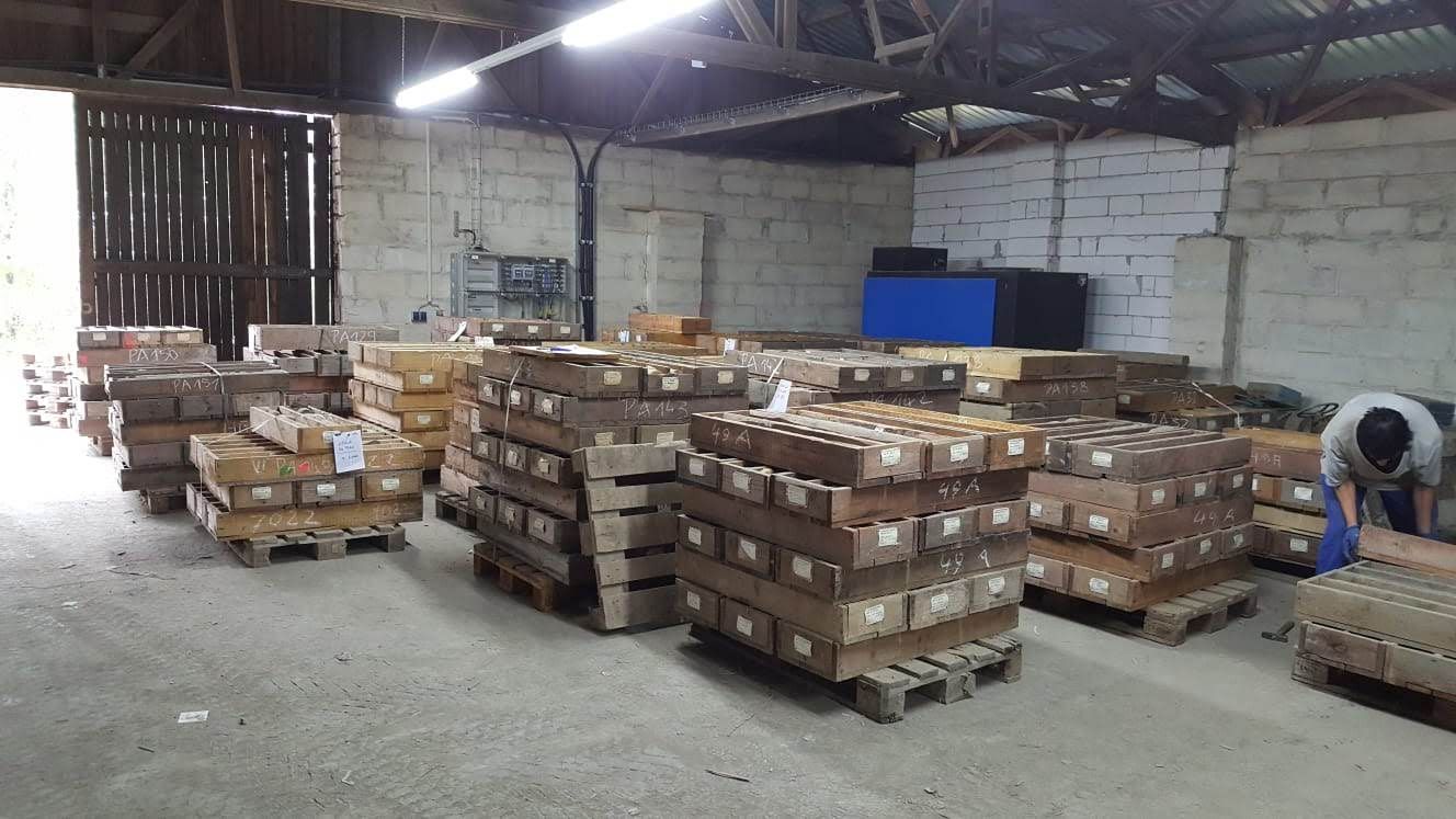 Innenansicht einer Lagerhalle mit Paletten, die mit Kisten beladen sind; eine Person ist bei der Arbeit.