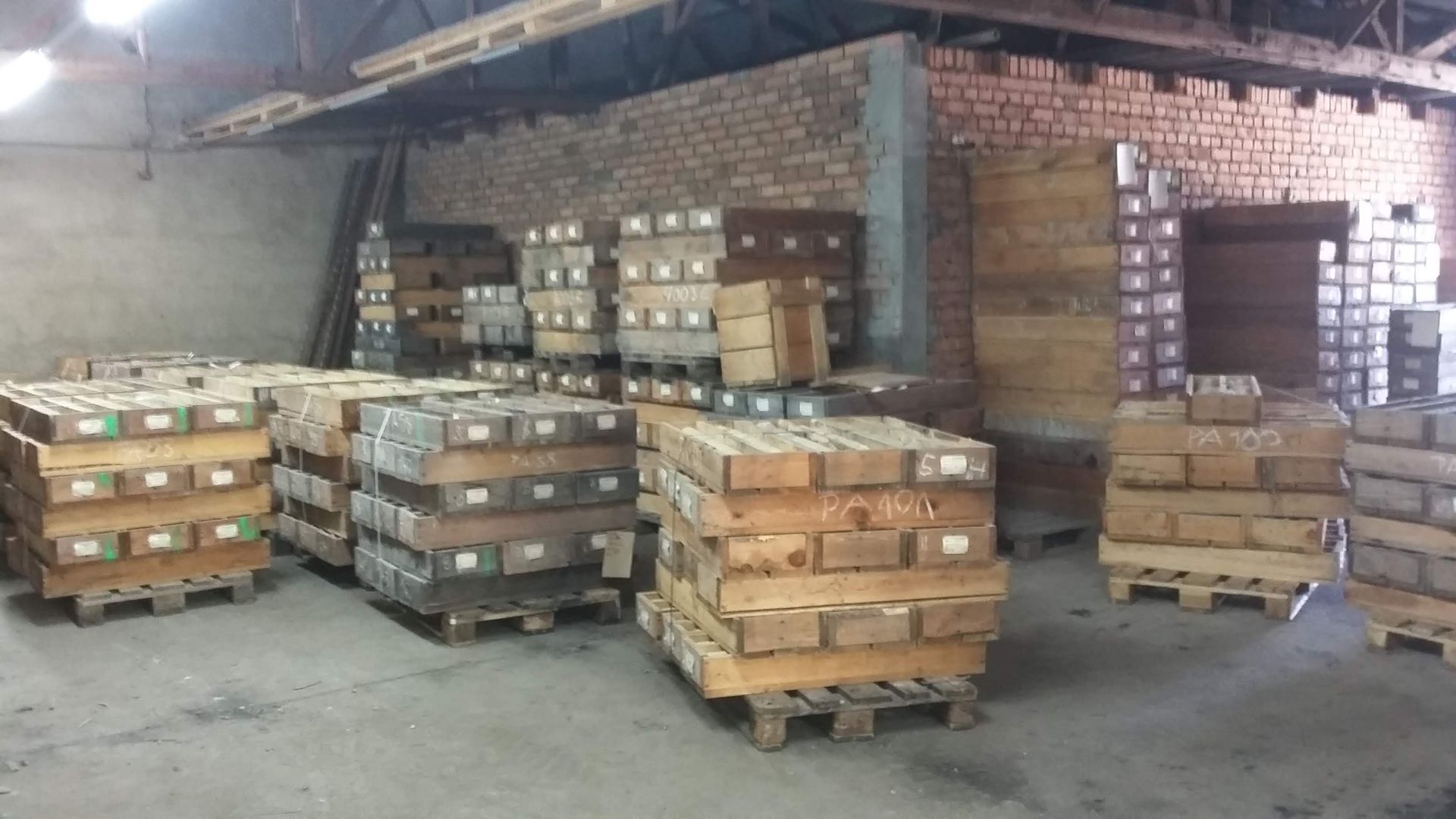 Ziegelstapel auf Holzpaletten in einem Backsteingebäude.