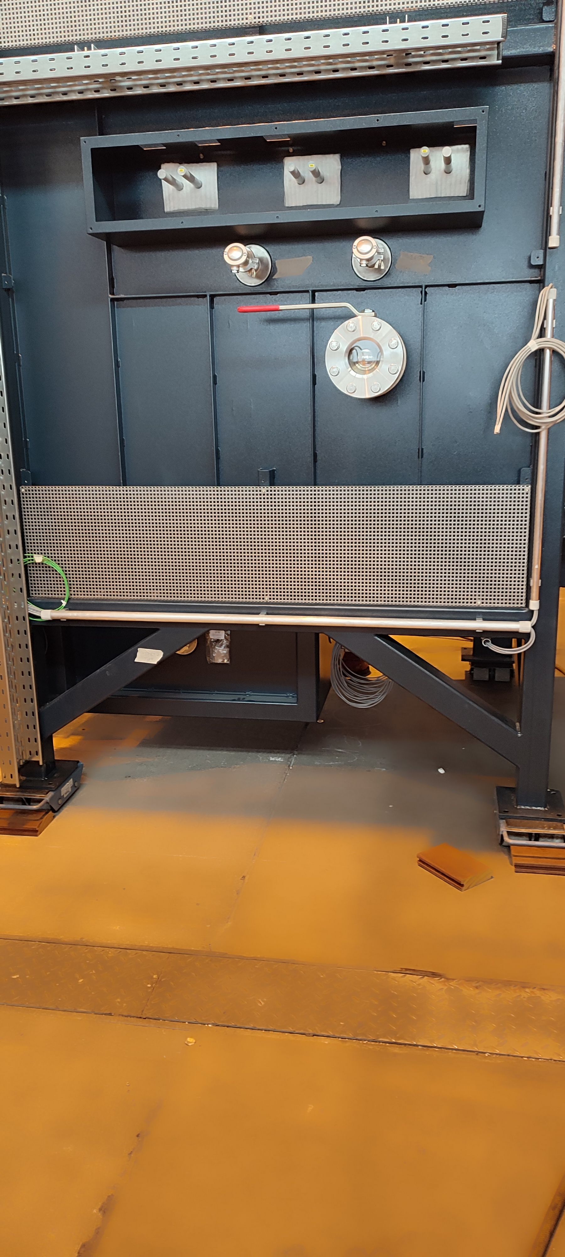 Große, dunkle Maschinen mit Metallgittern und -paneelen in einer Lagerhalle.