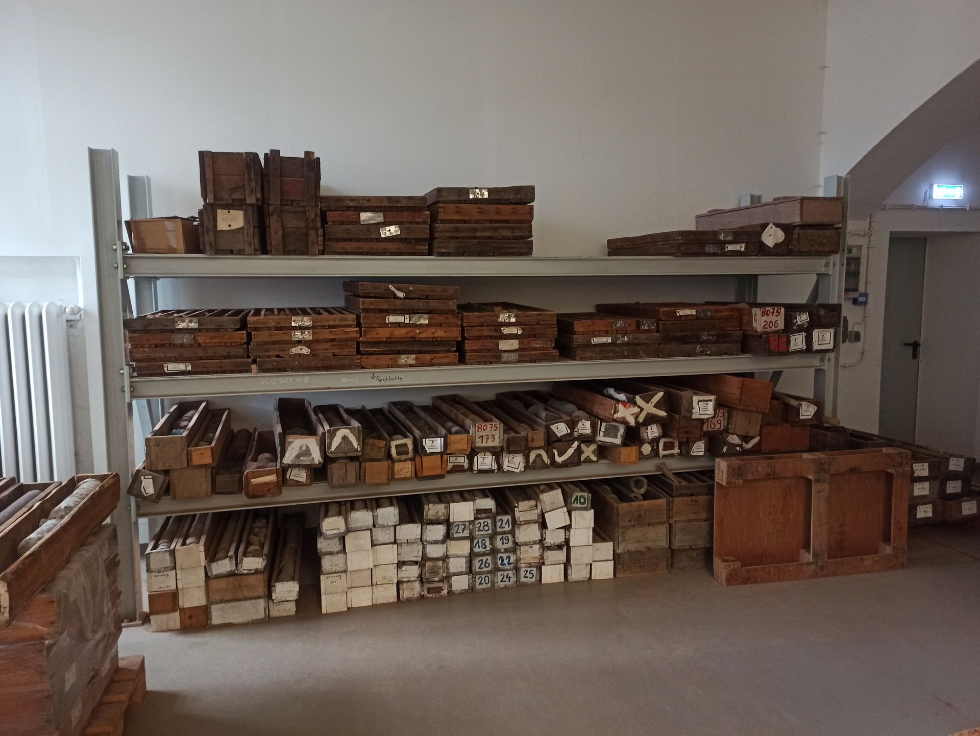 Regale mit vielen Holzgegenständen in einem weißen Raum.