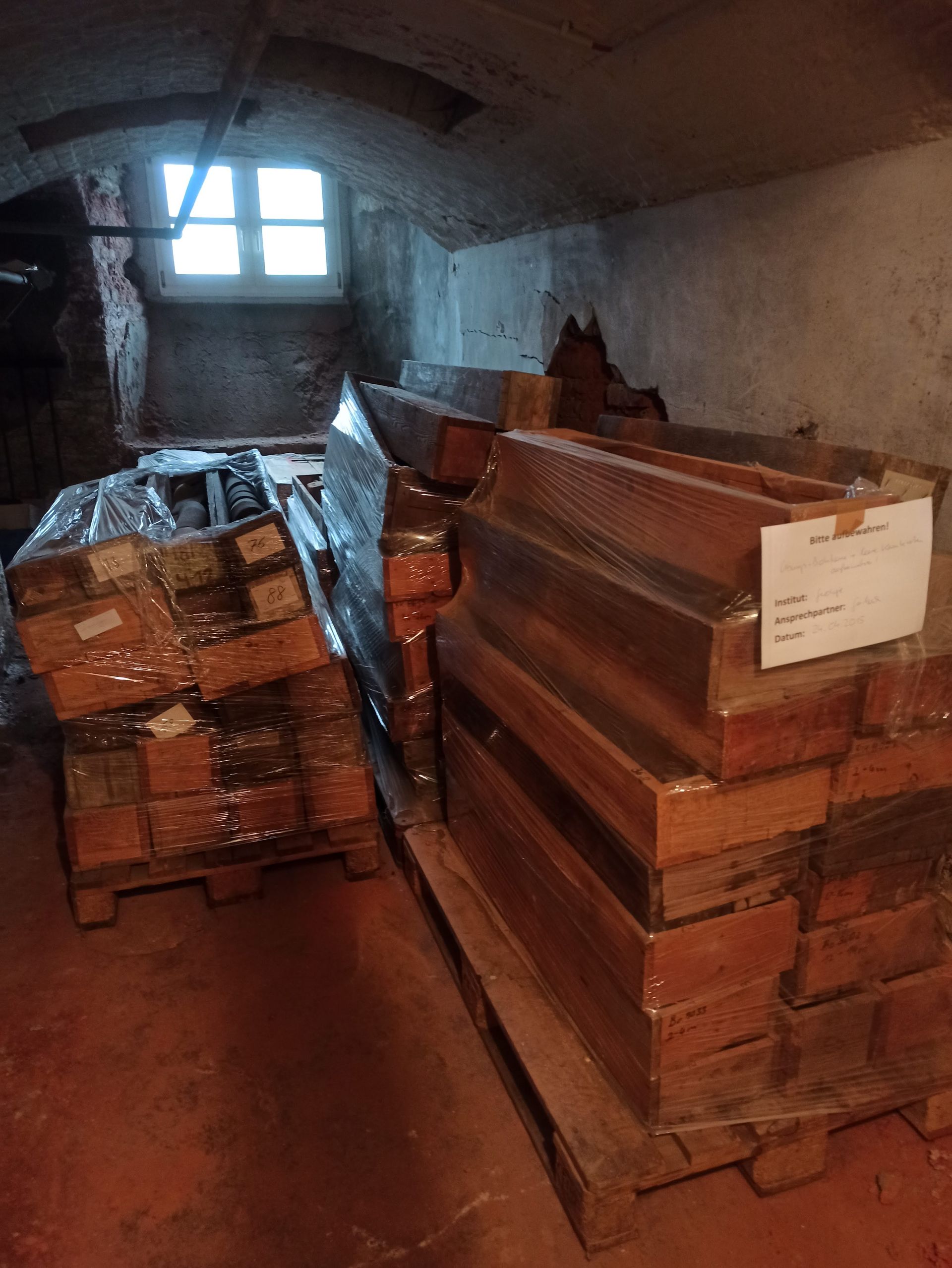 Stapelweise neue Ziegelsteine, verpackt auf Paletten, in einem dunklen Keller.