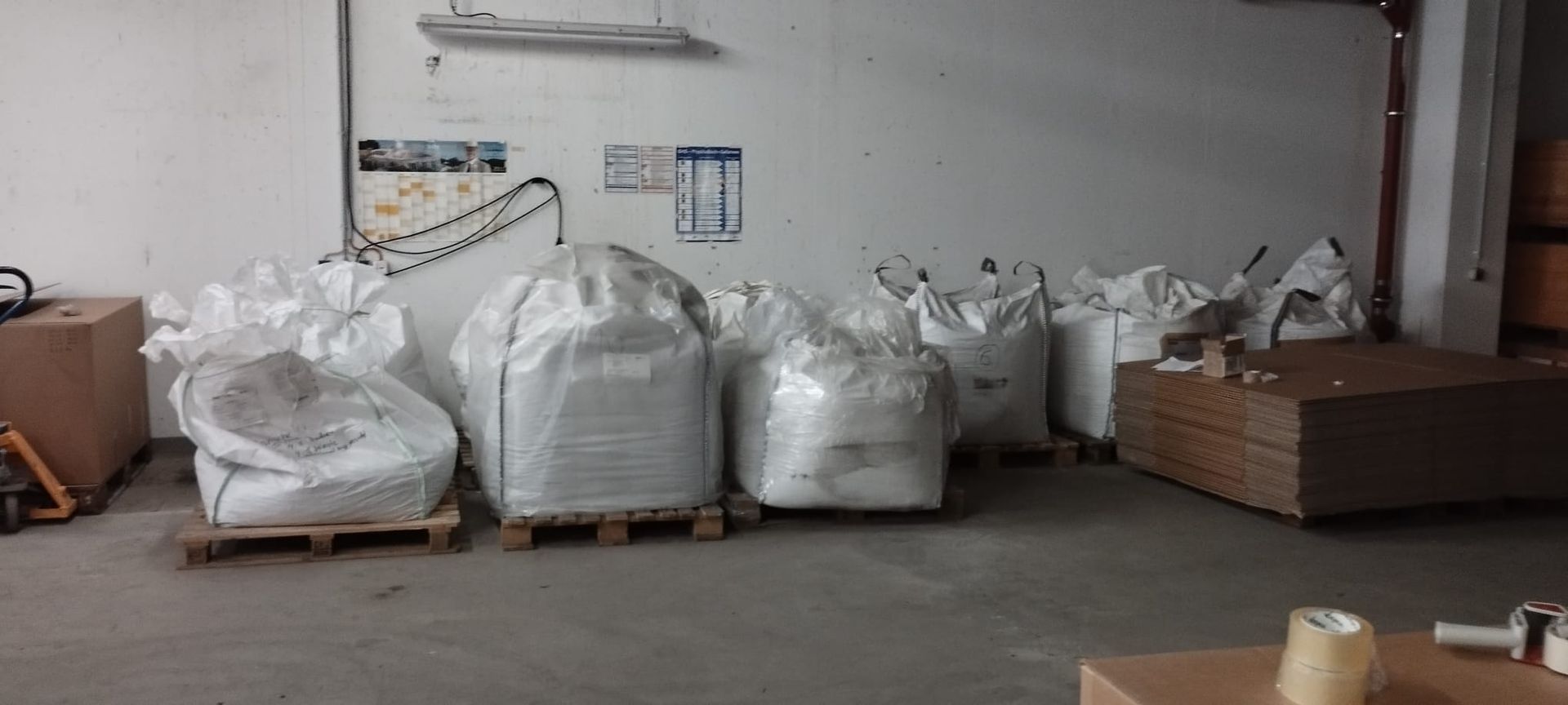 Große weiße Säcke auf Paletten in einem Lagerhaus.