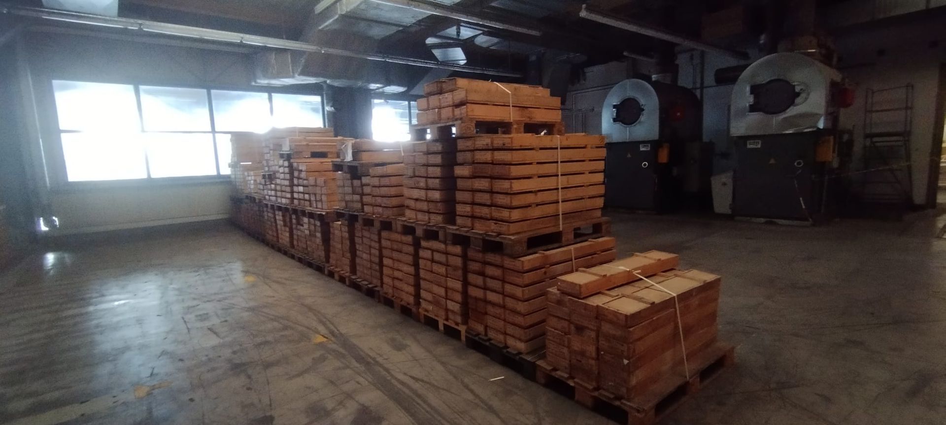 Paletten mit rechteckigen Ziegelsteinen sind in einem Lagerhaus in der Nähe eines großen Fensters gestapelt.