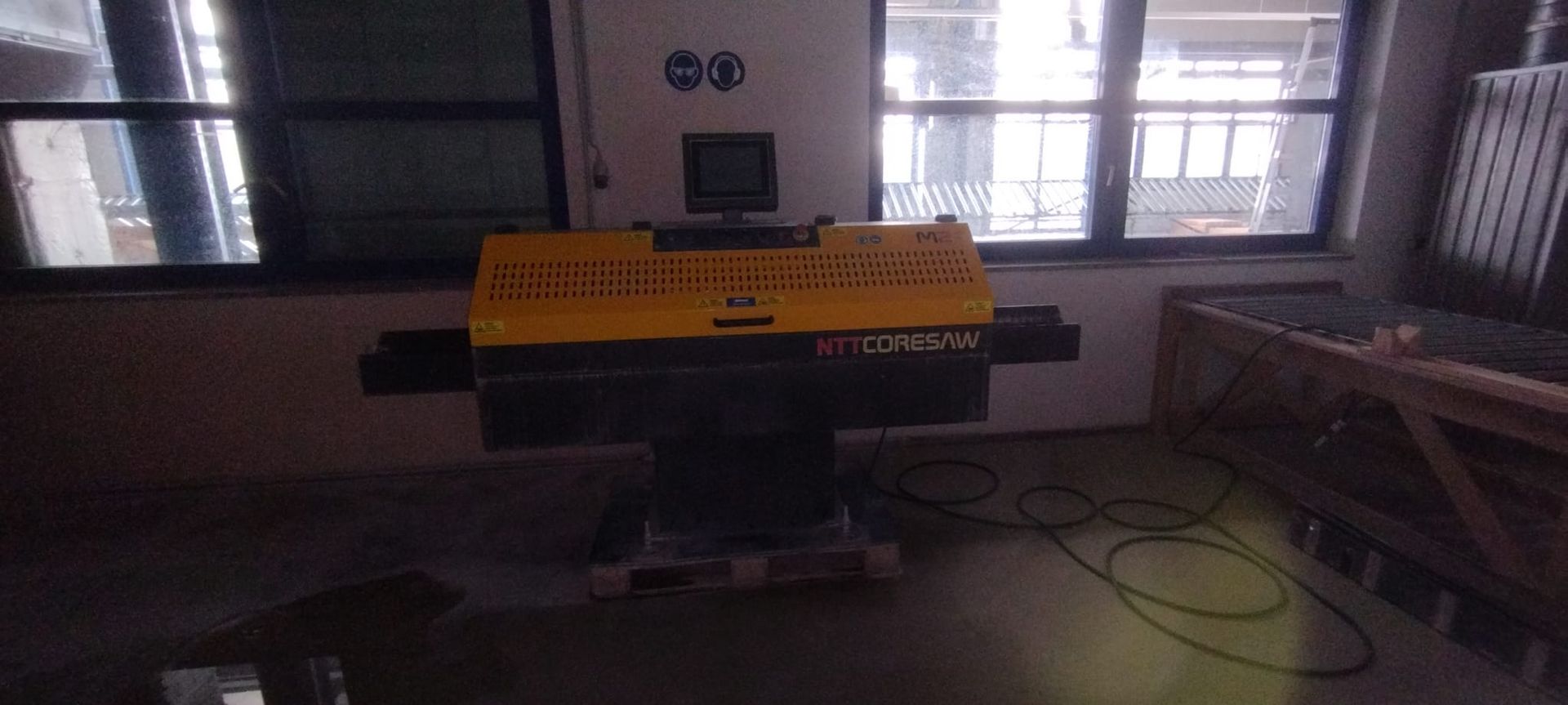 Gelbe und schwarze Industriemaschine in einer Lagerhalle, in der Nähe von Fenstern.